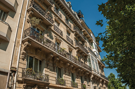 Leafy trees under sunny blue sky and building made in Parisian style of Paris. Known as the "City of Light", it is one of the most impressive cultural centers in the world. Northern France.のeditorial素材