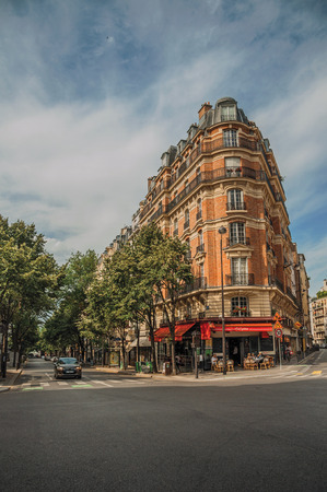Paris, northern France - July 09, 2017. Corner brick building with restaurant and trees in Paris. Known as the "City of Light", it is one of the most impressive cultural centers in the world.のeditorial素材