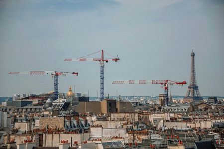 Close-up of buildings rooftops, cranes and Eiffel Tower on the horizon in Paris. Known as the "City of Light", it is one of the most impressive cultural centers in the world. Northern France.の写真素材