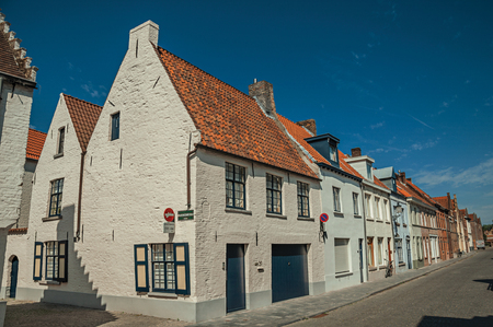 Brick facade of old houses with a sunny blue sky in an empty street of Bruges.の写真素材