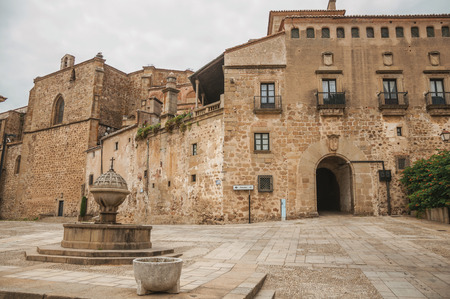 Fountain in the middle of deserted square encircled by gothic buildings with gateway arch in Plasencia. A cute, small countryside village, full of old buildings in western Spain.の写真素材