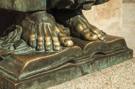 Caceres, Spain - July 03, 2018. Bronze statue of feet over book on the corner of the Santa Maria Cathedral at Caceres. A charming town with a fully preserved medieval city center in western Spain.の写真素材