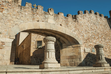 Big arched entrance to the historical city center on a stone wall with merlons, in a sunny day at...