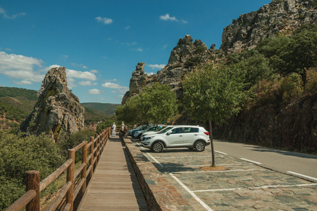 Cars parked next to the road through rocky cliffs covered by trees in sunny day at the Monfrague National Park. A remarkable place with a beautiful ridge and noted for its bird-life in western Spain.のeditorial素材