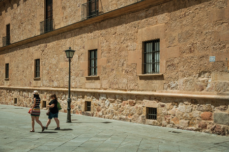 Salamanca, Spain - July 21, 2018. People walking an alley in front of faced from an old gothic building at Salamanca. This lovely medieval town is one of the most important university cities in Spain.のeditorial素材