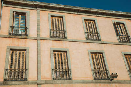 Windows with closed shutters and one of them open on an old building facade, in a sunny day at...