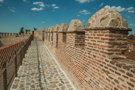 Pathway over old thick wall with battlement and large tower made of stone encircling the town of Avila. It has the longest and imposing wall completely encircling this well-kept gothic town in Spain.のeditorial素材