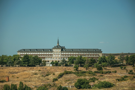 Large building with central tower on top of hill at countryside landscape at Avila outskirt. It has the longest and imposing wall completely encircling this well-kept gothic town in Spain.のeditorial素材