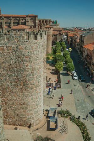 Avila, Spain - July 23, 2018. People walking on street in front of stone tower in wall around Avila. It has the longest and imposing wall completely encircling this well-kept gothic town of Spain.のeditorial素材