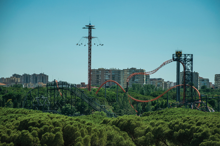 Roller coaster in amusement park on the horizon with trees in a sunny day, seen from the Teleferico Park of Madrid. Capital of Spain this charming metropolis has vibrant and intense cultural life.の写真素材
