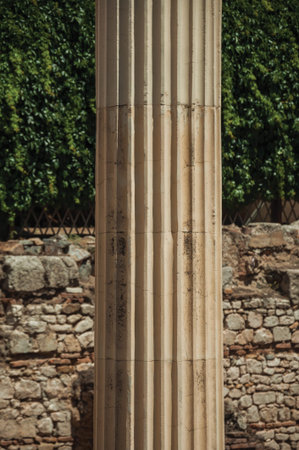 Close-up of marble columns in front of a stone wall, reminiscent of Roman Forum building in Merida....