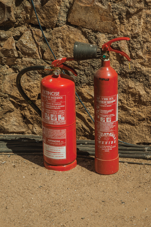 Merida, Spain - July 05, 2018. Fire extinguishers in front of stone wall at the Roman Theater of Merida. Founded by ancient Rome in western Spain, the city preserves many buildings of that era.のeditorial素材