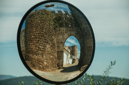 Stone tower at the main entrance doorway on a sunny day, reflected in street mirror at Evoramonte. A...