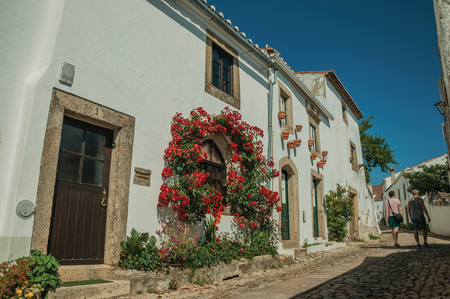 Marvao, Portugal - July 10, 2018. Cobblestone alley with people walking and facade of old flowered houses in Marvao. An amazing medieval fortified village on a granite crag in eastern Portugal.のeditorial素材