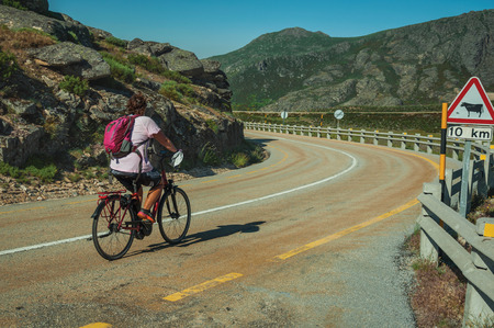 Serra da Estrela, Portugal - July 12, 2018. Cyclist on road passing on rocky landscape and fields at the Serra da Estrela. The highest mountain range in continental Portugal, with astonishing sceneryのeditorial素材