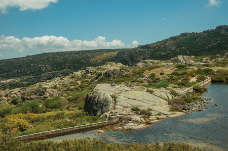 People resting on a big rock at the Covao dos Conchos dam lake on the highlands, in a sunny day at the Serra da Estrela. The highest mountain range in continental Portugal, with astonishing scenery.の写真素材