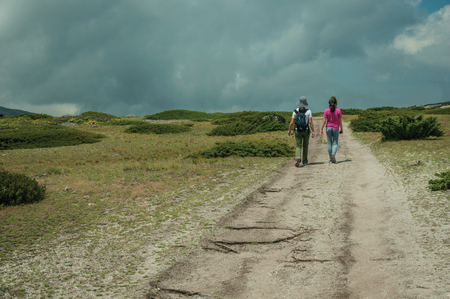 Serra da Estrela, Portugal - July 12, 2018. Woman and girl walking along a trail on highlands at the Serra da Estrela. The highest mountain range in continental Portugal, with astonishing scenery.のeditorial素材