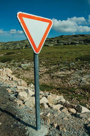 YIELD traffic signpost on roadside and rocky landscape with green bushes, on the highlands of the Serra da Estrela. The highest mountain range in continental Portugal, with astonishing scenery.の写真素材