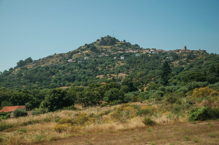 Hilly landscape covered by trees and rocks in a sunny day, with the small Monsanto village on top of it. This township is considered one of the cutest and most peculiar historic village of Portugal.の写真素材