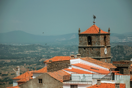 Rooftops of old stone houses and church steeple with clock, on hilly landscape in a sunny day at Monsanto. Considered one of the cutest and most peculiar historic village of Portugal.の写真素材