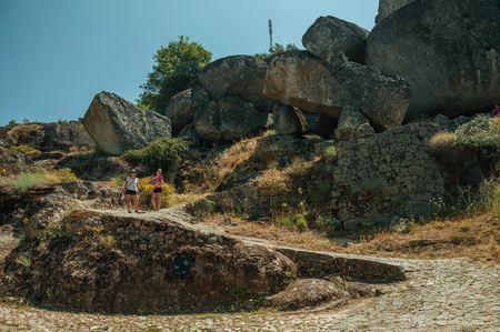 Monsanto, Portugal - July 13, 2018. Woman and child walking by a cobblestone path with rocks and dry bushes at Monsanto. Considered one of the cutest and most peculiar historic village of Portugalのeditorial素材