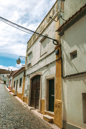 Old houses with doors on alley with cobblestone pavement in sunny day at Estremoz. A nice little historic town with several buildings made of marble on eastern Portugal.の写真素材