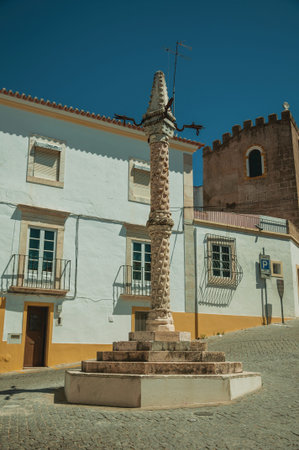 Deserted square of Santa Clara with marble pillory in the Manueline style and old buildings, on...