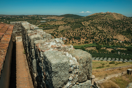 Pathway on top of thick stone wall in a sunny day, with the Fort of Nossa Senhora da GraÃ§a on top of hill at Elvas. A gracious star-shaped fortress city on the easternmost frontier of Portugal.の写真素材