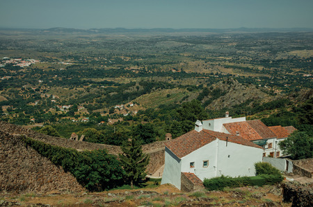 Long outer stone wall and old white houses with hilly landscape in background, on sunny day at Marvao. An amazing medieval fortified village perched on a granite crag in eastern Portugal.の写真素材