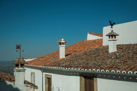 Chimneys over rooftop of old houses with whitewashed wall and countryside landscape, in a sunny day at Marvao. An amazing medieval fortified village perched on a granite crag in eastern Portugal.の写真素材