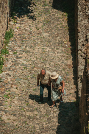 Castelo de Vide, Portugal - July 10, 2018. Old couple walking on cobblestone path inside the Castelo...
