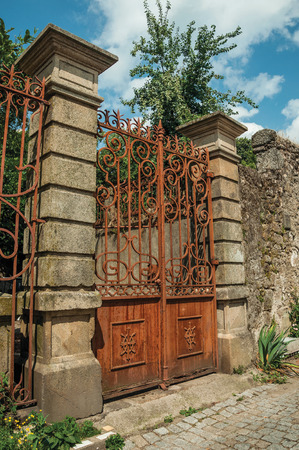 Vintage wrought iron gate covered by rust, in front of old mansion facade with stone decoration at Covilha. Known as the town of wool and snow, stands at Estrela ridge proximity in eastern Portugal.の写真素材