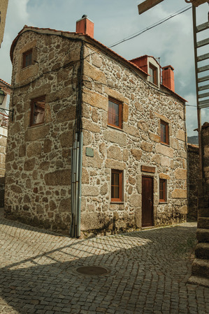 Charming facade of old house with stone wall in a deserted alley, on a cloudy day at Sabugueiro. A nice village in the middle of the Serra da Estrela, an amazing mountain range in eastern Portugal.の写真素材