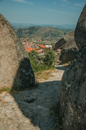 Pathway passing through big round rocks and the Monsanto village underneath the hilly landscape. This township is considered one of the cutest and most peculiar historic village of Portugal.の写真素材