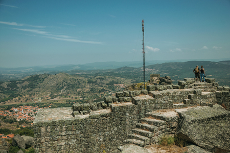 Couple looking the countryside landscape from the stone wall on rocky hill, in a sunny day at the Castle of Monsanto. Considered one of the cutest and most peculiar historic village of Portugal.の写真素材