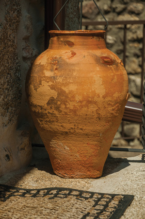 Close-up of clay pot in antique style in front of iron railing, on a sunny day at Linhares da Beira. A medieval hamlet with unique architectural diversity fruit of several times, in eastern Portugal.の写真素材