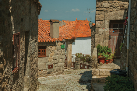 Charming old houses and flowered pots on cobblestone alley, in a sunny day at Linhares da Beira. A medieval hamlet with unique architectural diversity fruit of several times, in eastern Portugal.の写真素材