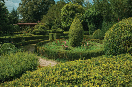 Leafy green bushes on a garden with gravel pathway and trees, in a sunny day at Gouveia. A nice country town with gardens and captivating historical heritage in Portugal.の写真素材
