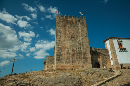 Wooden cross and square tower with stone walls over rocky hill, in a sunny day at the medieval Belmonte Castle. A small town, birthplace of the navigator Pedro Alvares Cabral, on eastern Portugal.のeditorial素材