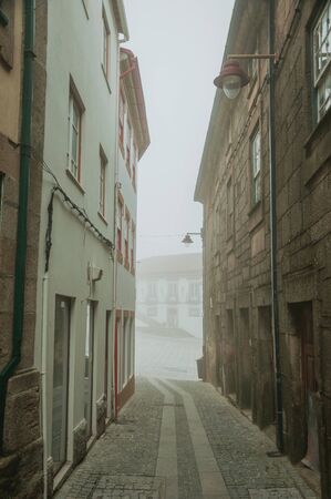 Narrow deserted alley with old terraced houses and street light, in the morning mist at Guarda. This friendly and well-kept medieval town is the highest in the continental Portugal.の写真素材