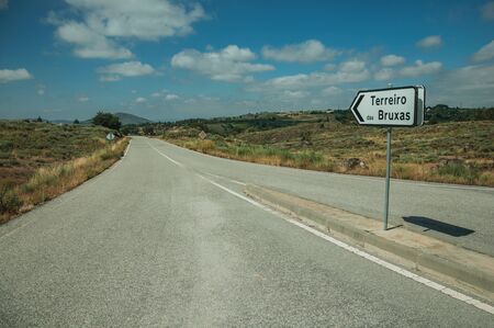 Road on rural landscape with a signpost indicating a nearby village called âwitch yardâ, in a sunny day near Sortelha. One of the most astonishing and well preserved medieval villages in all Portugal.の写真素材