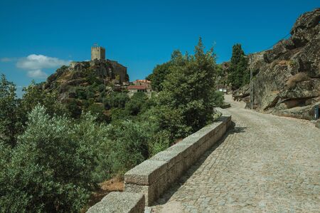 Deserted street going towards the historical city center on hilly landscape with trees, in a sunny day at Sortelha. One of the most astonishing and well preserved medieval villages in all Portugal.の写真素材