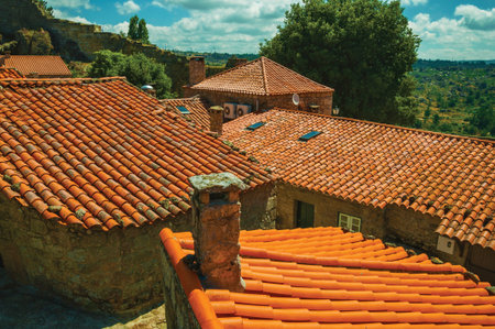 Chimneys over rooftops of old houses and countryside landscape, in a sunny day at Sortelha. One of...