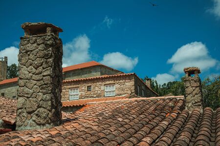 Rooftops covered by moss and lichens on old houses with chimneys and leafy treetops, in a sunny day at Sortelha. One of the most astonishing and well preserved medieval villages in all Portugal.の写真素材