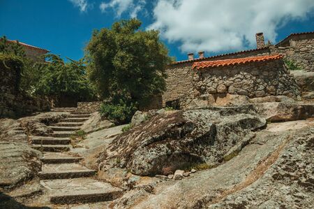 Gothic houses made of stone with leafy trees and stairway on slope, in a sunny day at Sortelha. One of the most astonishing and well preserved medieval villages in all Portugal.の写真素材