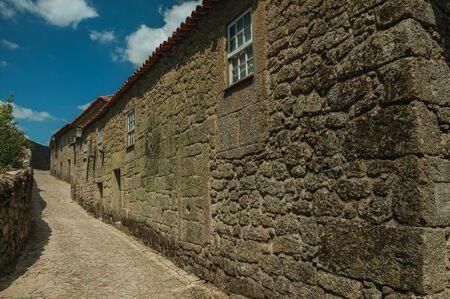 Gothic house with wall made of stone and wooden windows in a deserted alley on slope, in a sunny day at Sortelha. One of the most astonishing and well preserved medieval villages in all Portugal.の写真素材