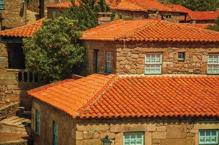 Gothic houses made of stone and leafy orange tree, in a sunny day at Sortelha. One of the most astonishing and well preserved medieval villages in all Portugal. Retouched photo.の写真素材