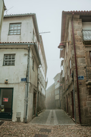 Guarda, Portugal - July 20, 2018. Old terraced houses and narrow deserted alley, in the morning mist at Guarda. This friendly and well-kept medieval town is the highest in the continental Portugal.のeditorial素材