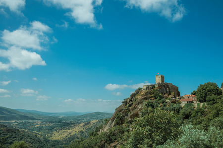 Hilly landscape with stone walls and tower of Castle over rocky cliff covered by trees, in a sunny day at Sortelha. One of the most astonishing and well preserved medieval villages in all Portugal.のeditorial素材