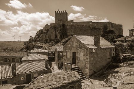 Old stone houses on alley and Castle with tower on top of cliff, in a sunny day at Sortelha. One of the most astonishing and well preserved medieval villages in all Portugal. Black and white photo.のeditorial素材